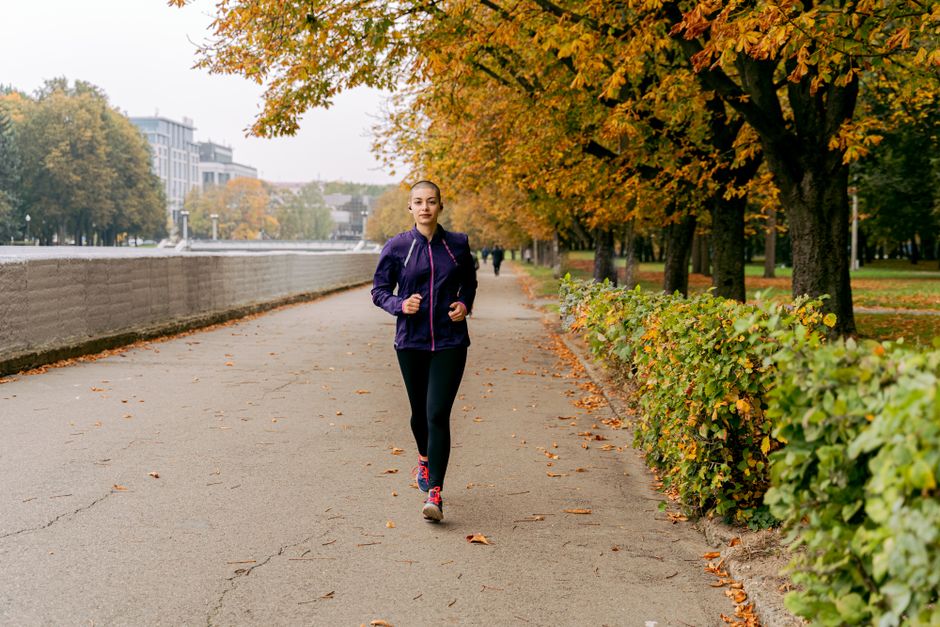 A woman jogging on a tree-lined path